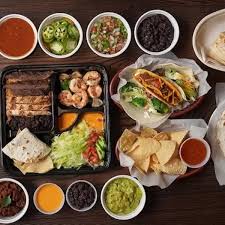 Tacos and sides in paper trays on a wood table