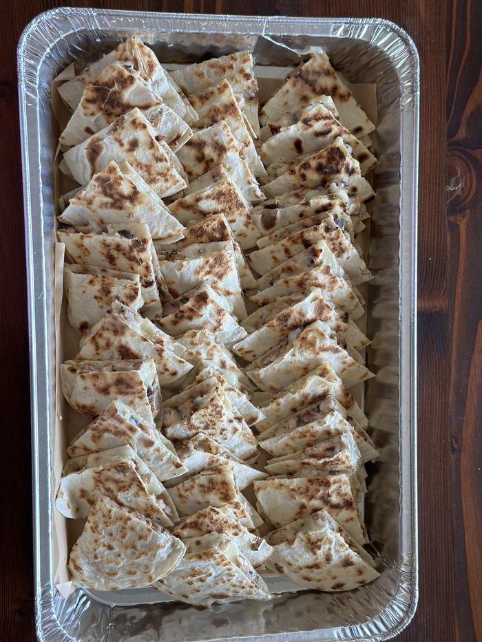 A full foil tray of quesadilla triangles, grilled and cut for a party
